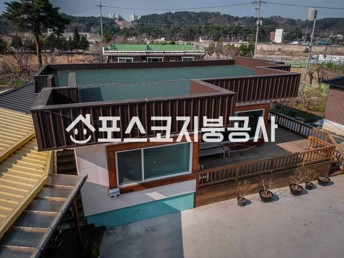 단층 주택 평지붕 옥상을 초록 칼라강판으로 덮고 둘레를 갈색 칼라강판으로 마감한 모습